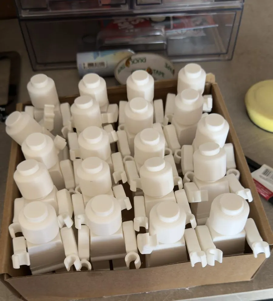 A cardboard tray holding a grid of white 3D printed LEGO-style figures